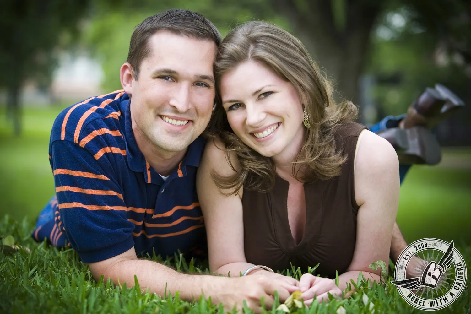 Smiling couple lying together on green grass in Austin, TX.
