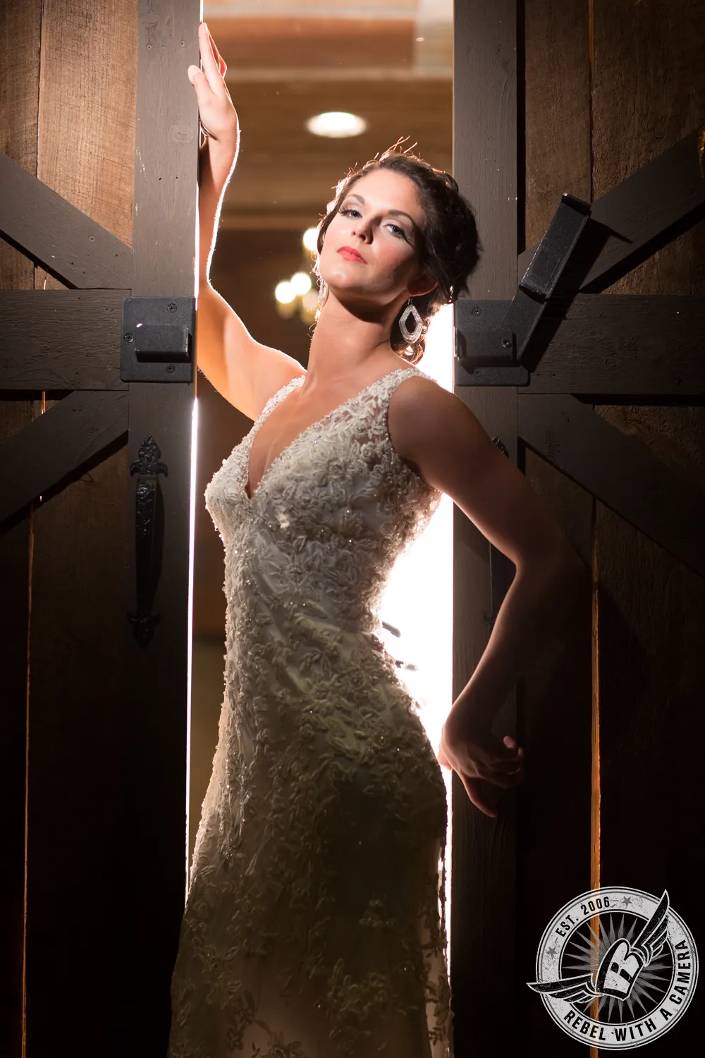 Bride in a lace wedding gown standing in a rustic doorway with one arm raised in Austin, Texas.