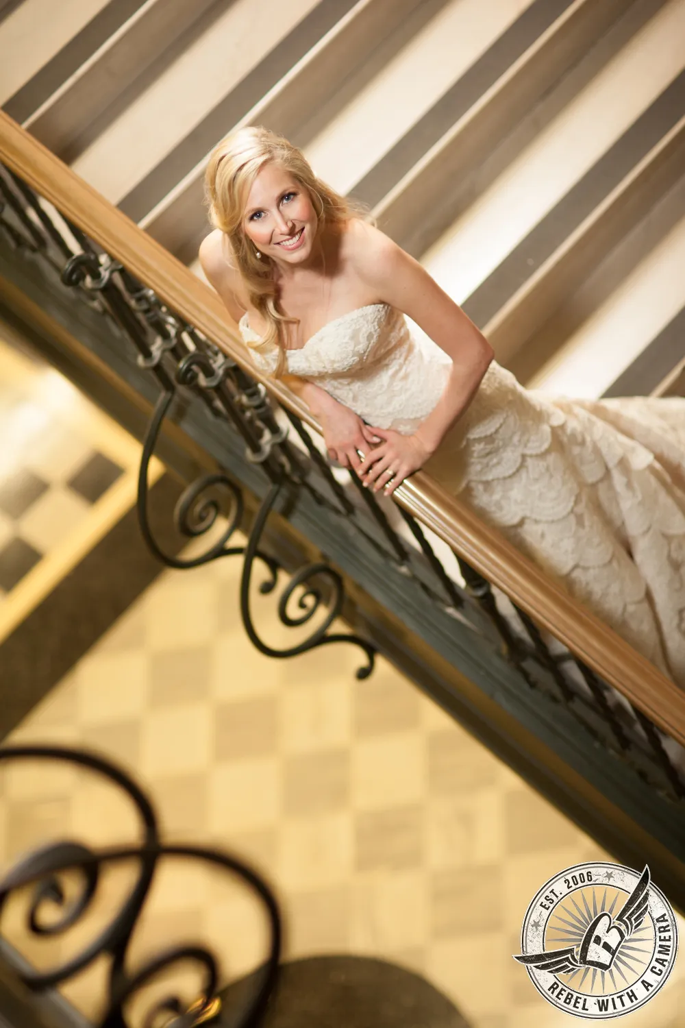 Bride in a strapless wedding gown leaning on an ornate staircase railing in Austin, Texas.