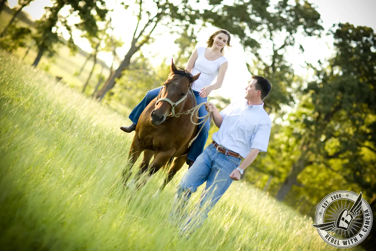 Couple riding a horse through a sunlit grassy field in Austin, TX.