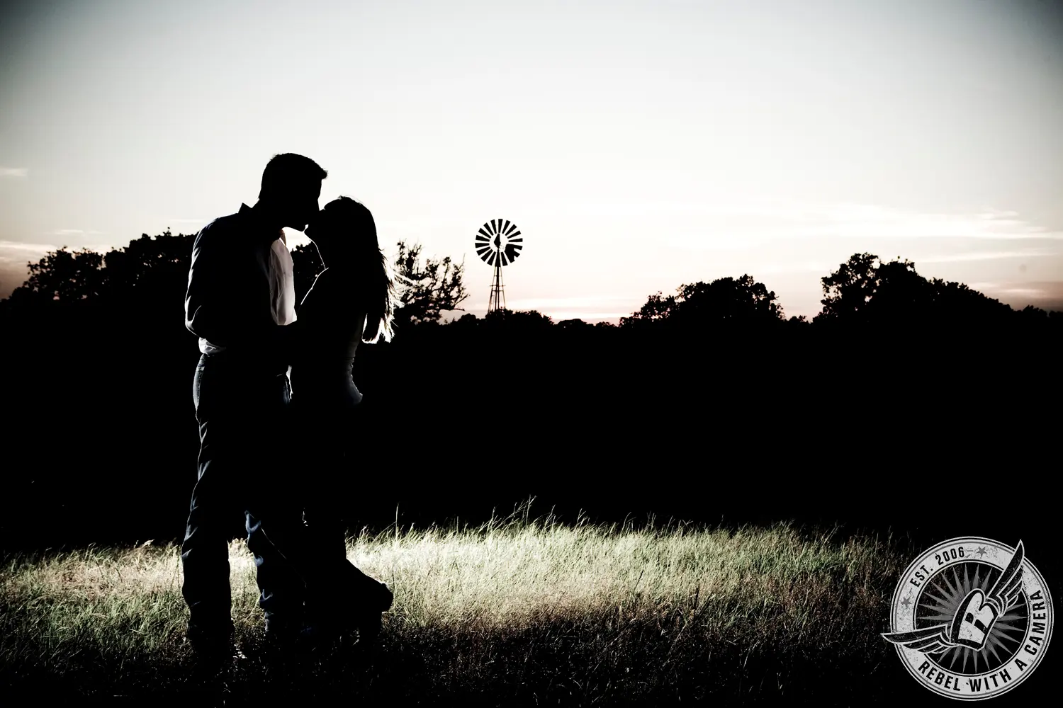Couple silhouetted and kissing in a field beside a windmill in Austin, TX.