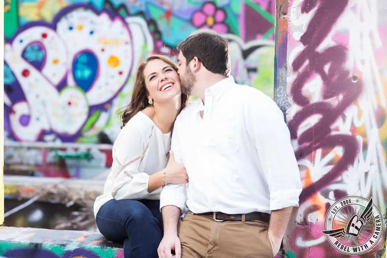 Smiling couple posing in front of colorful graffiti in Austin, TX.