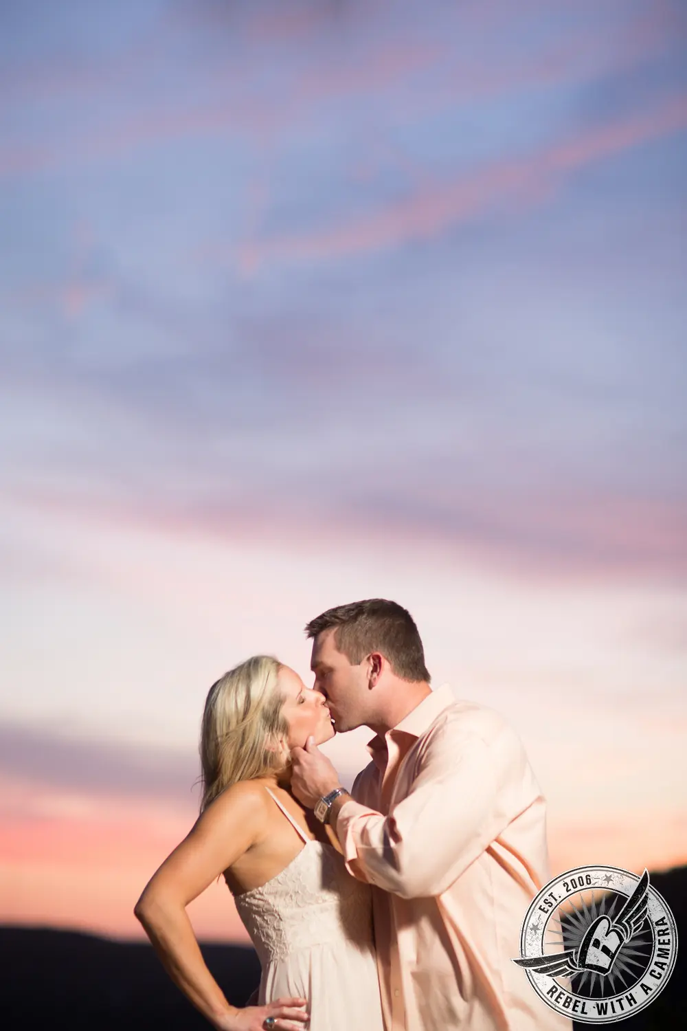 Couple kissing beneath a pastel sunset sky in Austin, TX.