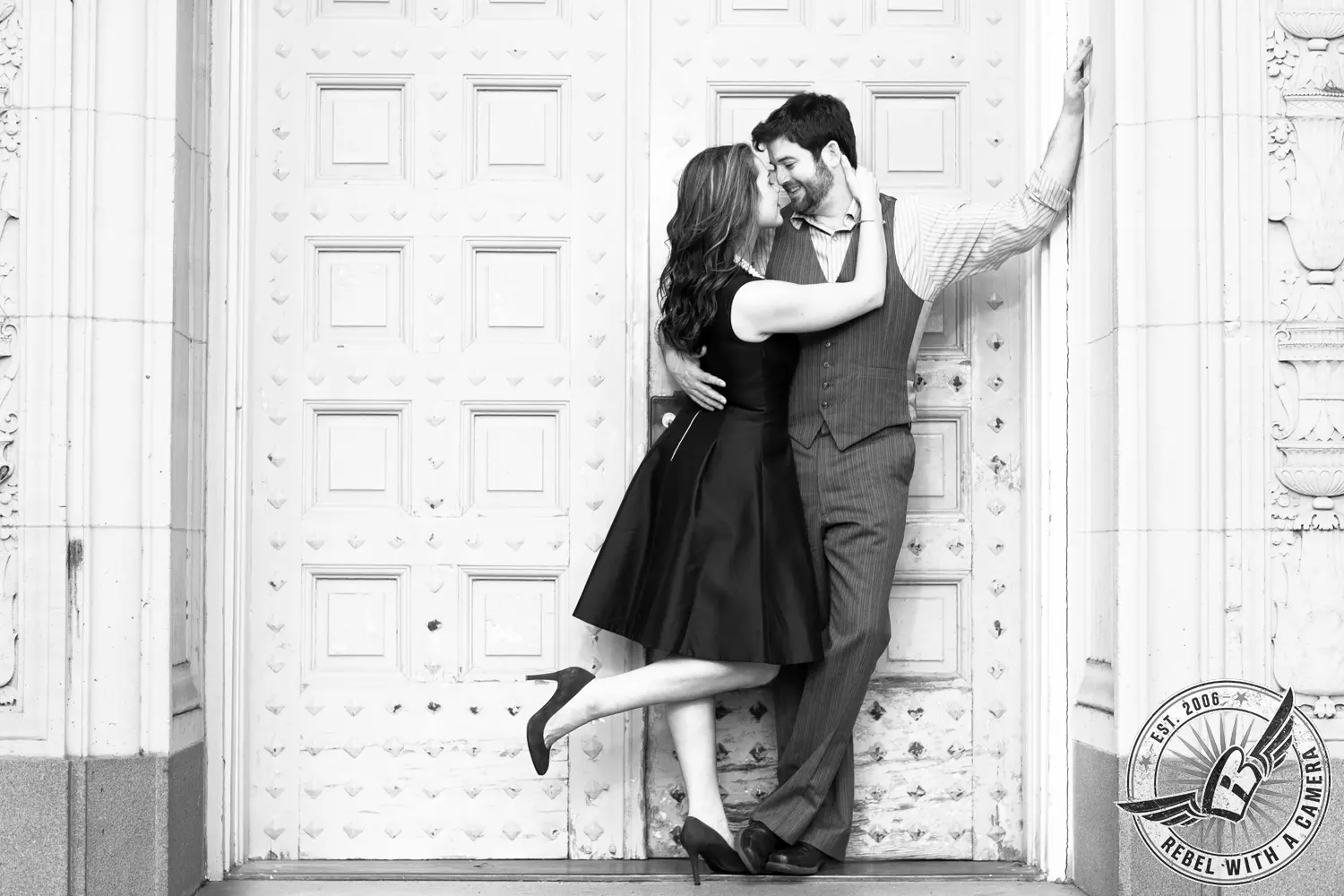 Black and white couple embracing in front of an ornate door in Austin, TX.