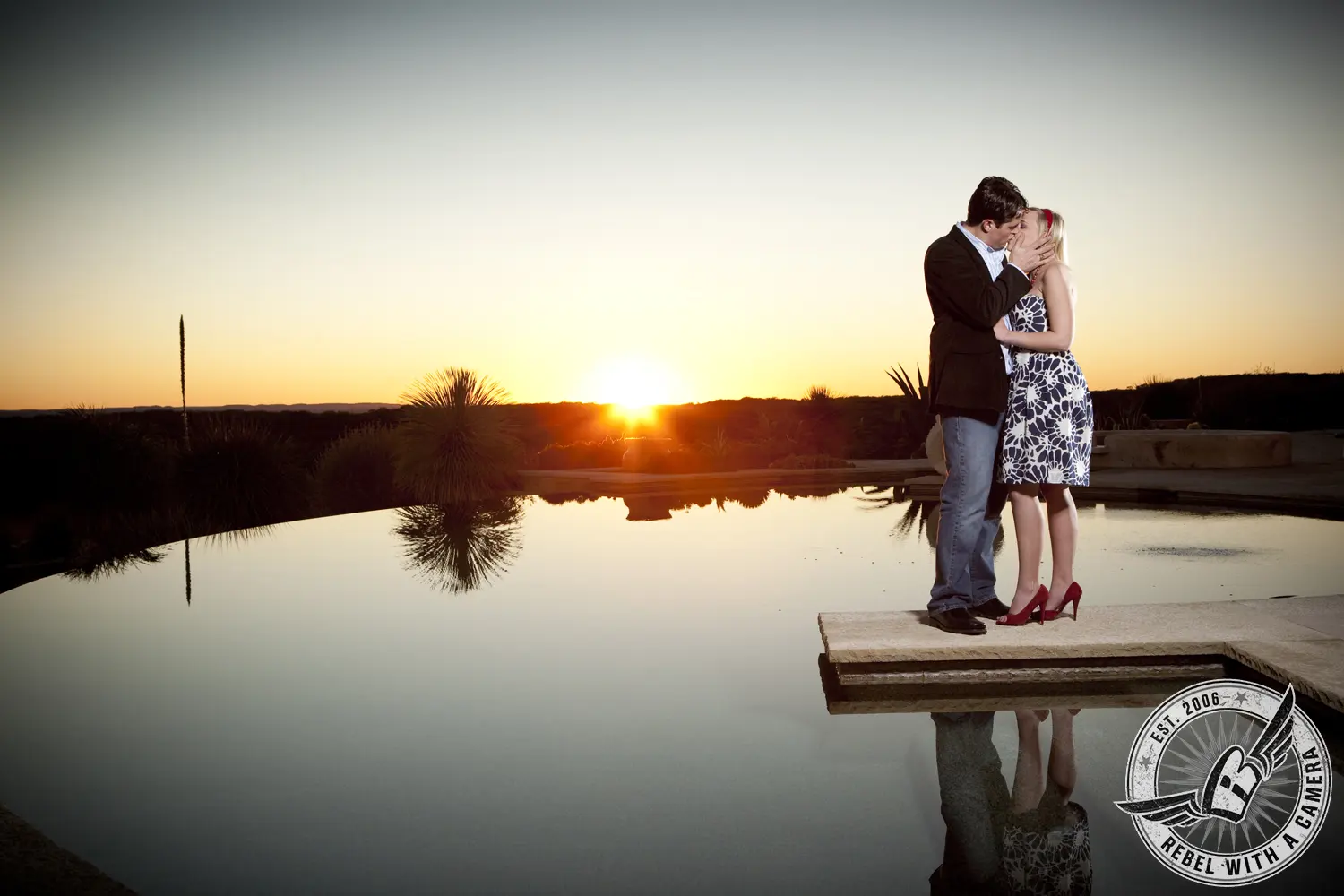 Couple kissing beside a reflective pond at sunset in Austin, TX.