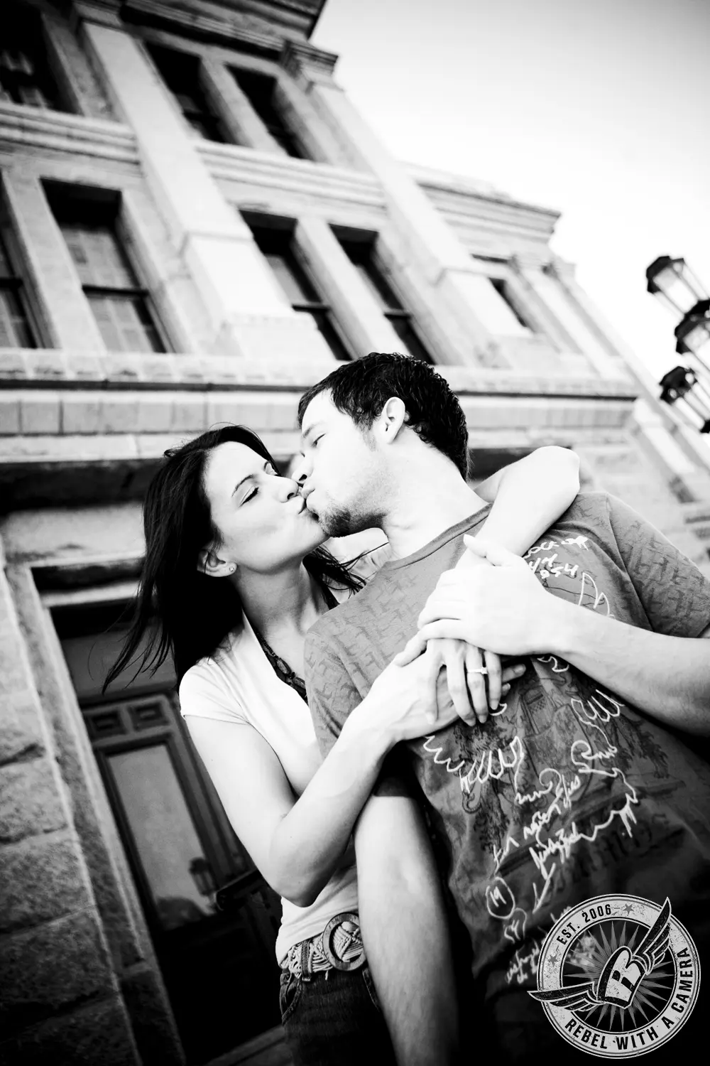 Black and white couple kissing beneath a large building in Austin, TX.