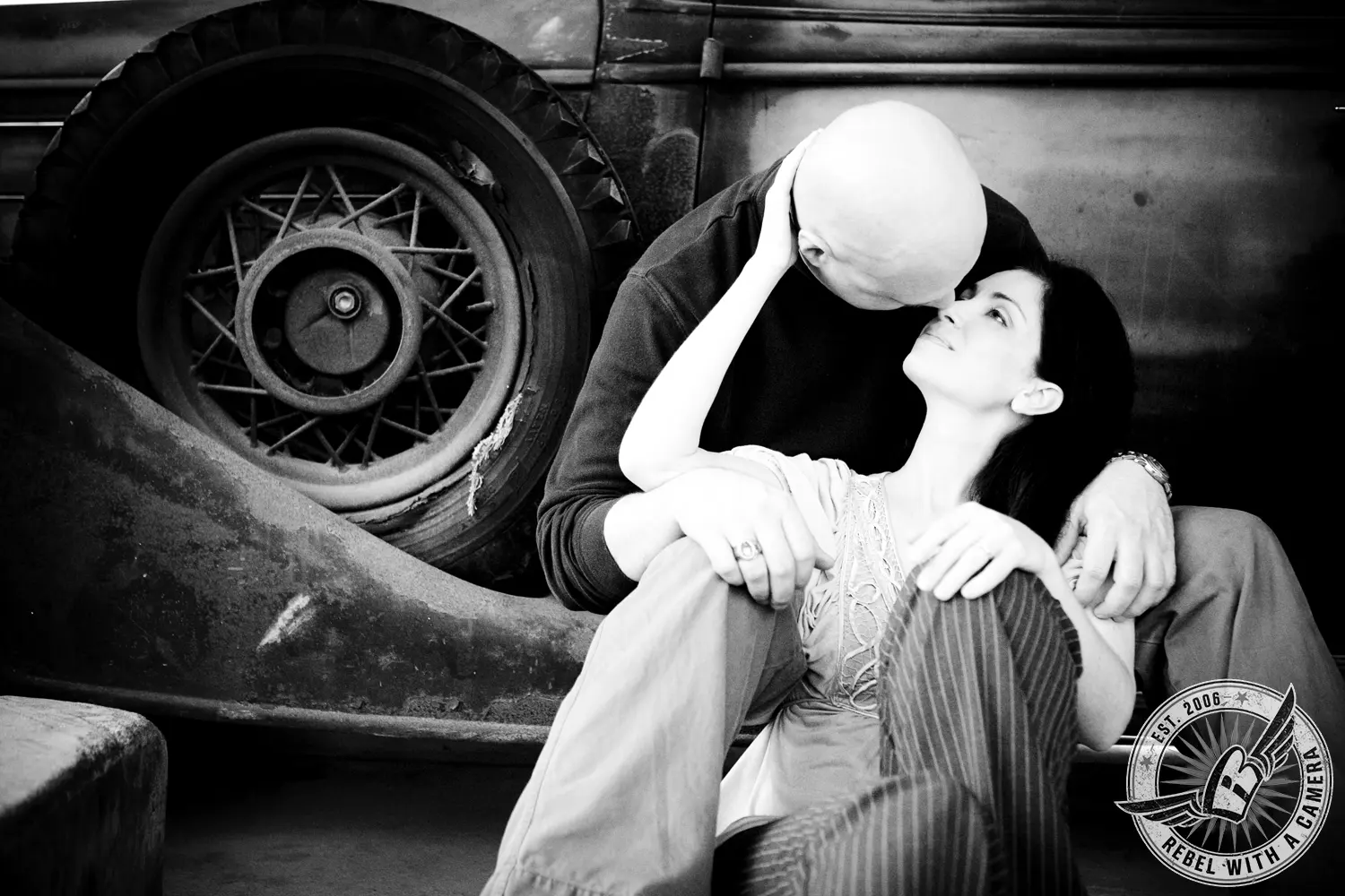 Black and white couple embracing beside a vintage vehicle in Austin, TX.