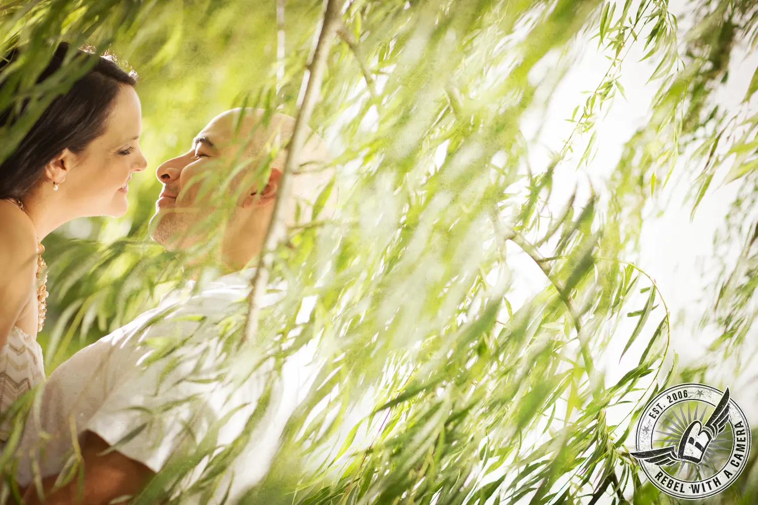 Couple facing each other through bright willow branches in Austin, TX.
