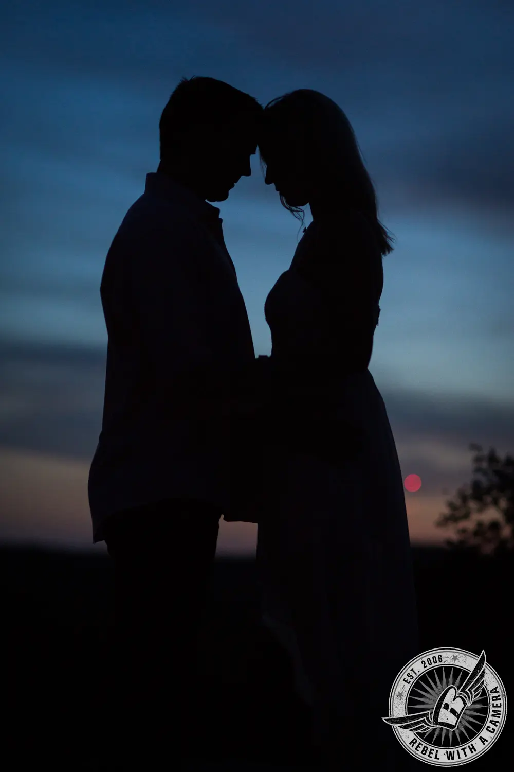 Silhouetted couple standing close together at dusk in Austin, TX.
