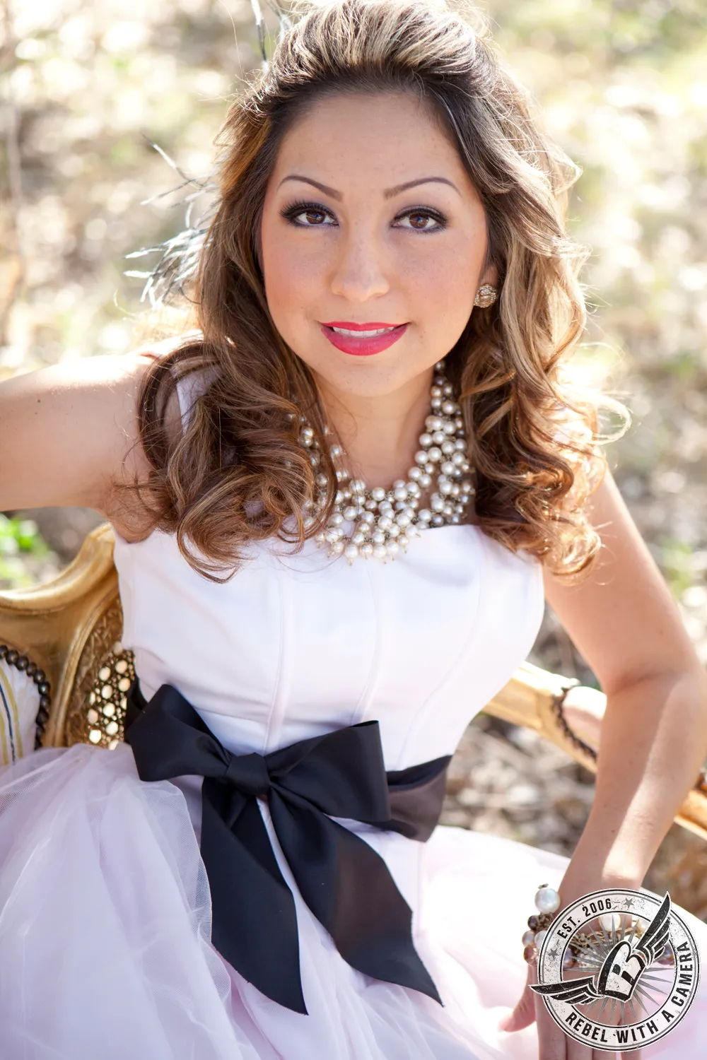 Portrait of a bride in a white dress with layered pearl necklaces and a black bow