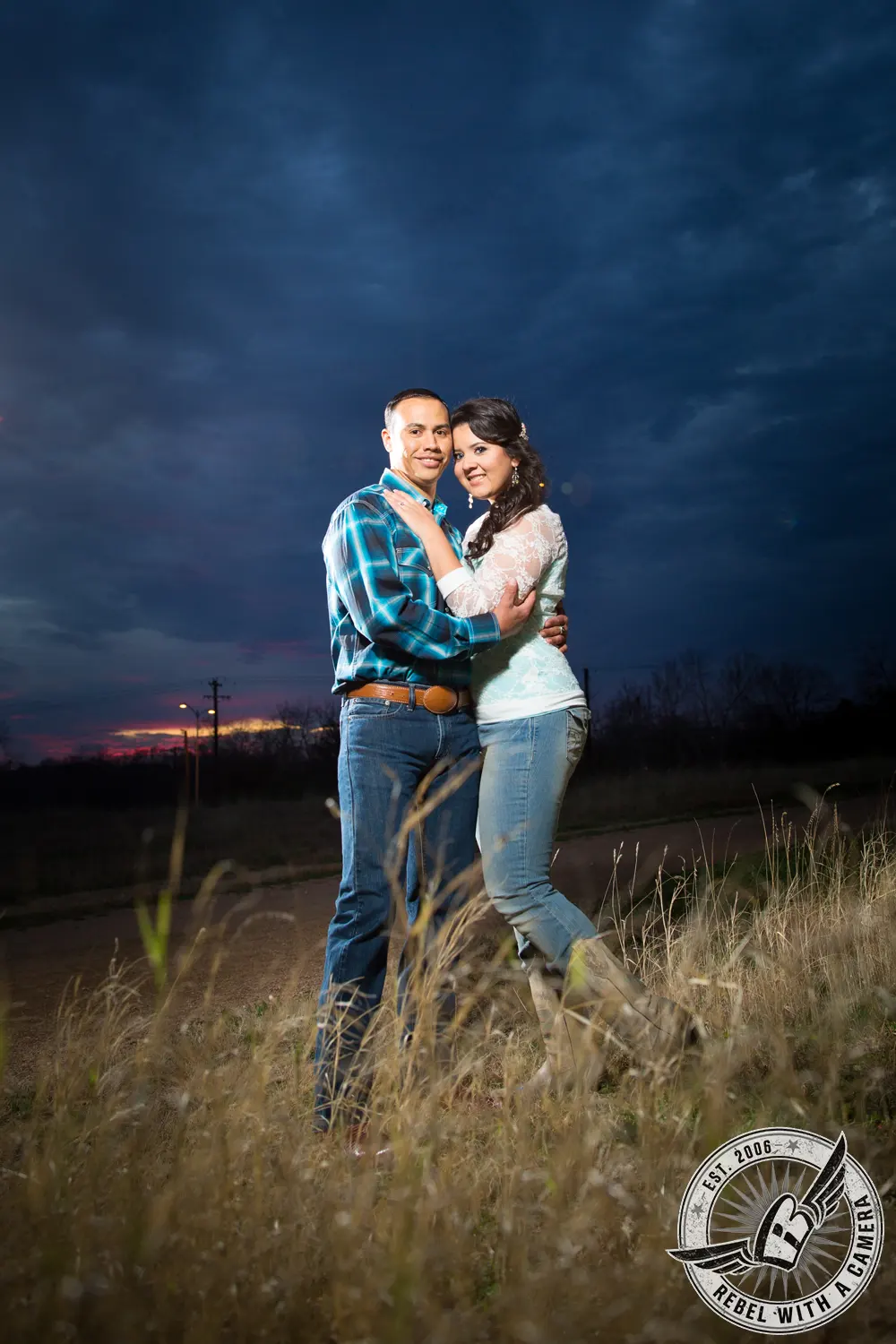 Couple embracing on a rural road beneath a dark blue evening sky in Austin, TX.
