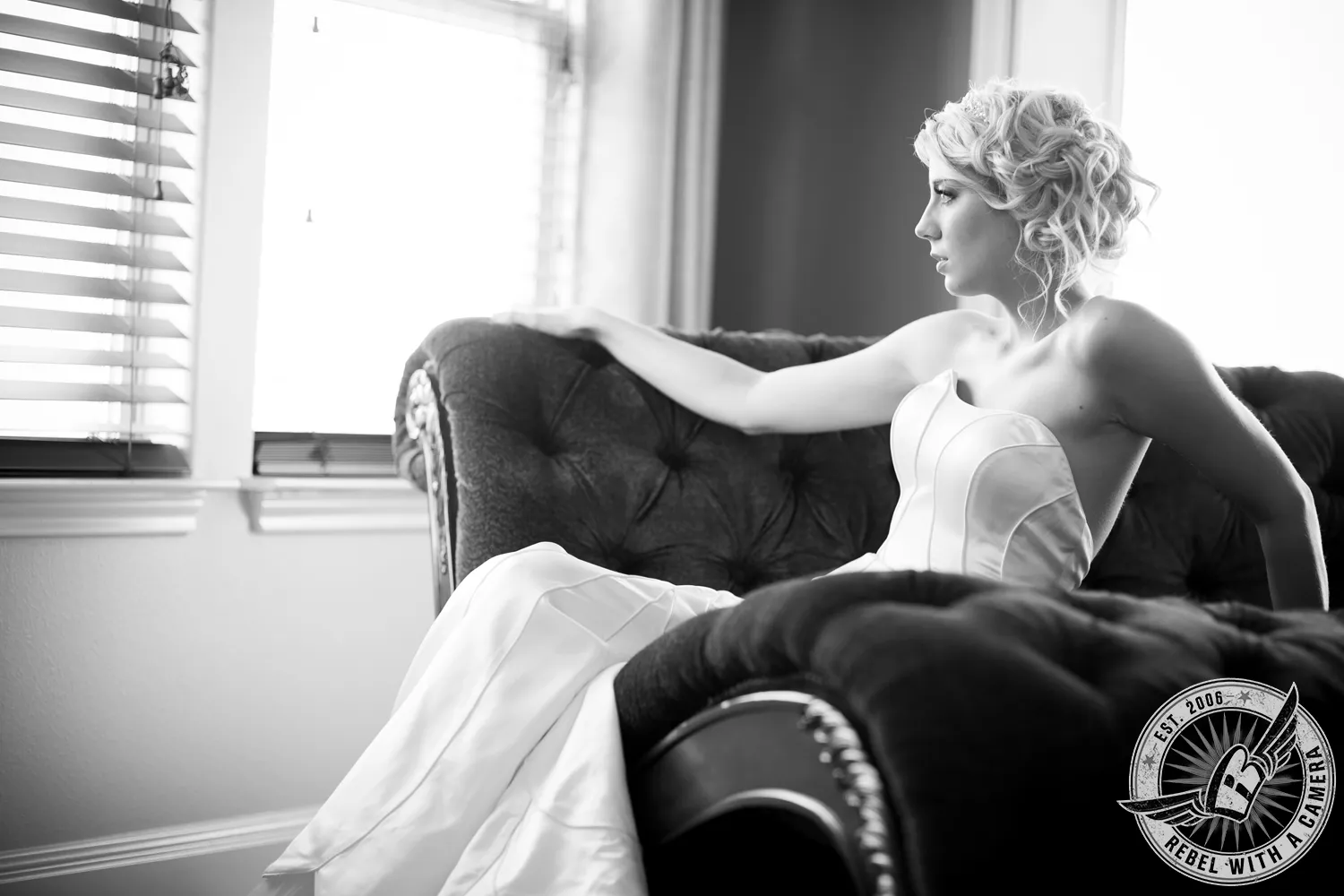 Black-and-white portrait of a bride reclining on a tufted sofa in a strapless gown in Austin, TX.