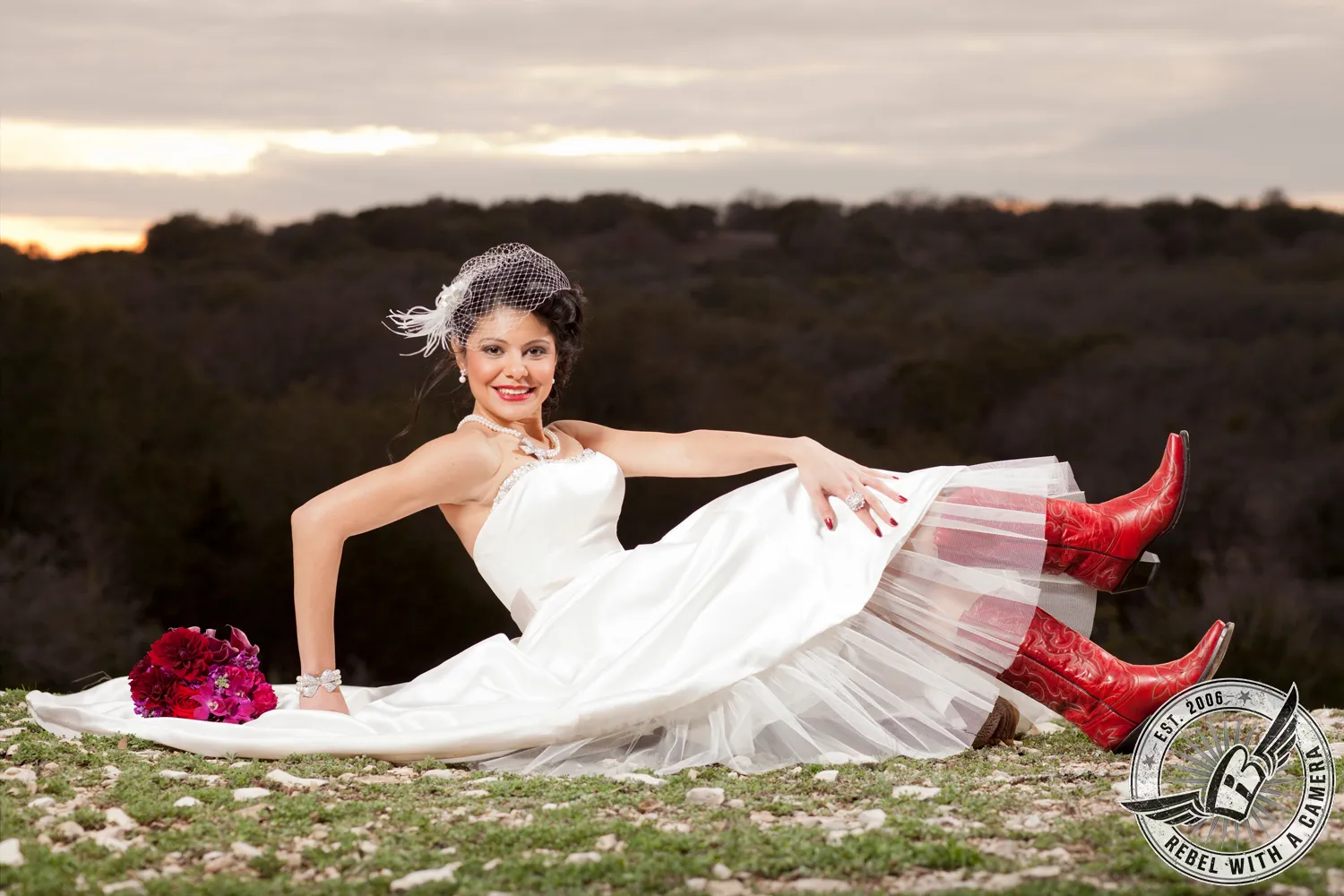Bride reclining outdoors in a white dress and red cowboy boots