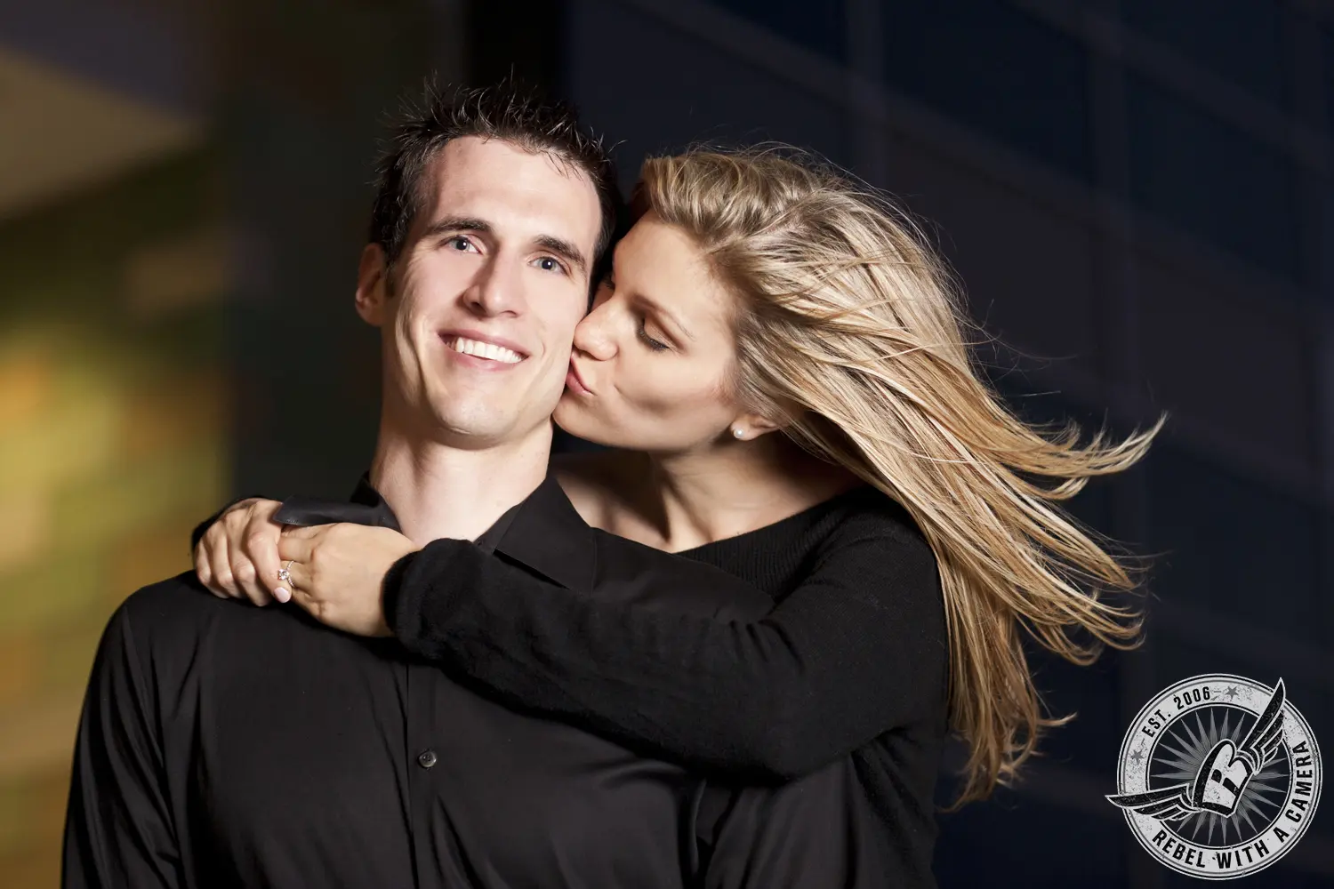 Woman kissing smiling man on the cheek in a close portrait in Austin, TX.