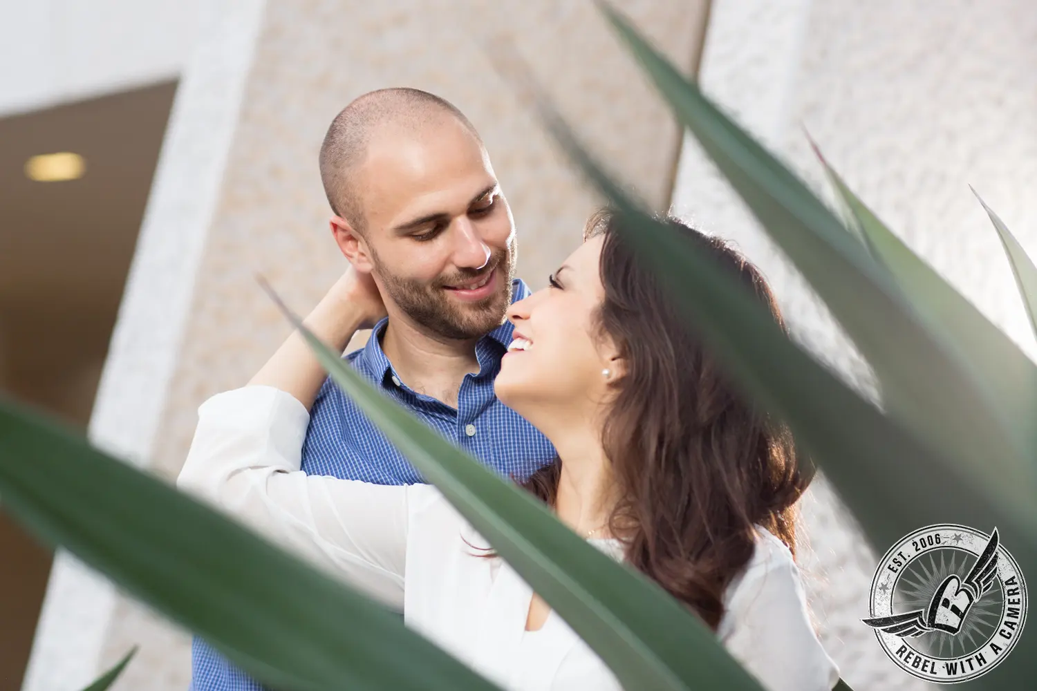 Couple smiling at each other through large agave leaves in Austin, TX.