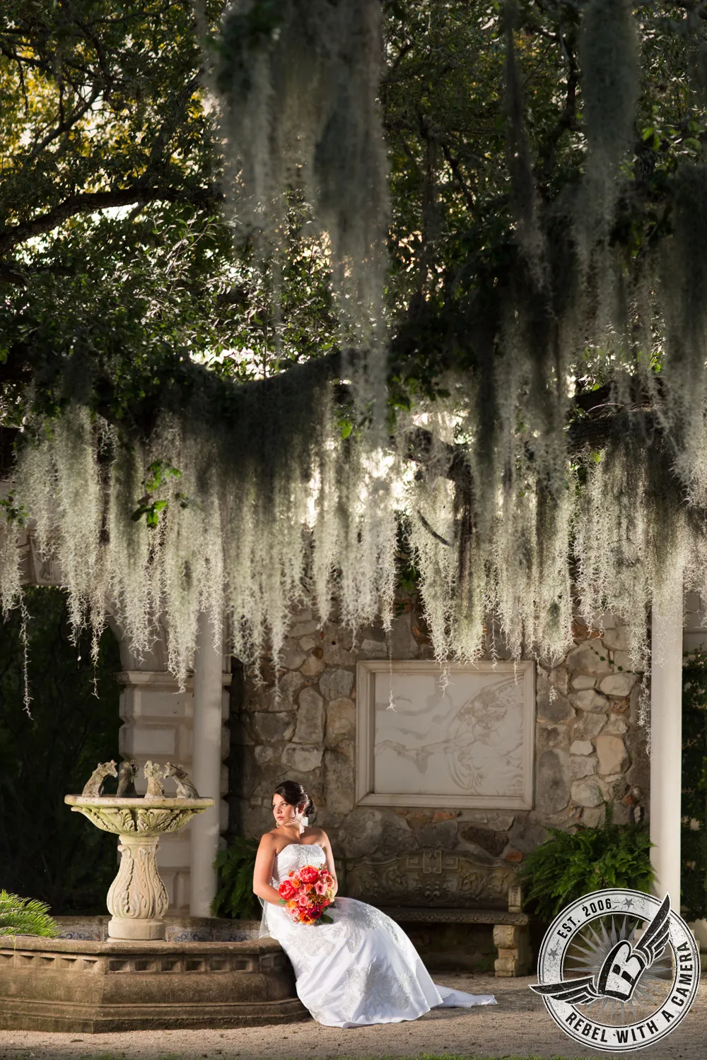 Bride seated beneath hanging Spanish moss with a bouquet in Austin, TX.