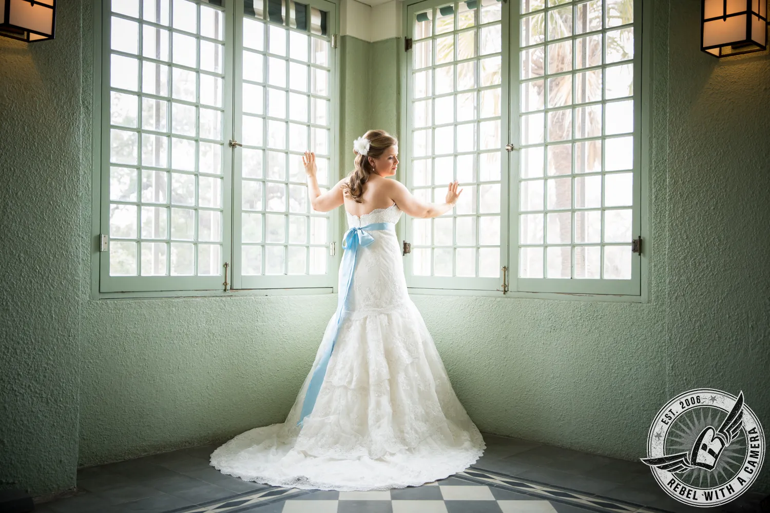 Bride in a white wedding dress standing before tall windows in Austin, Texas.