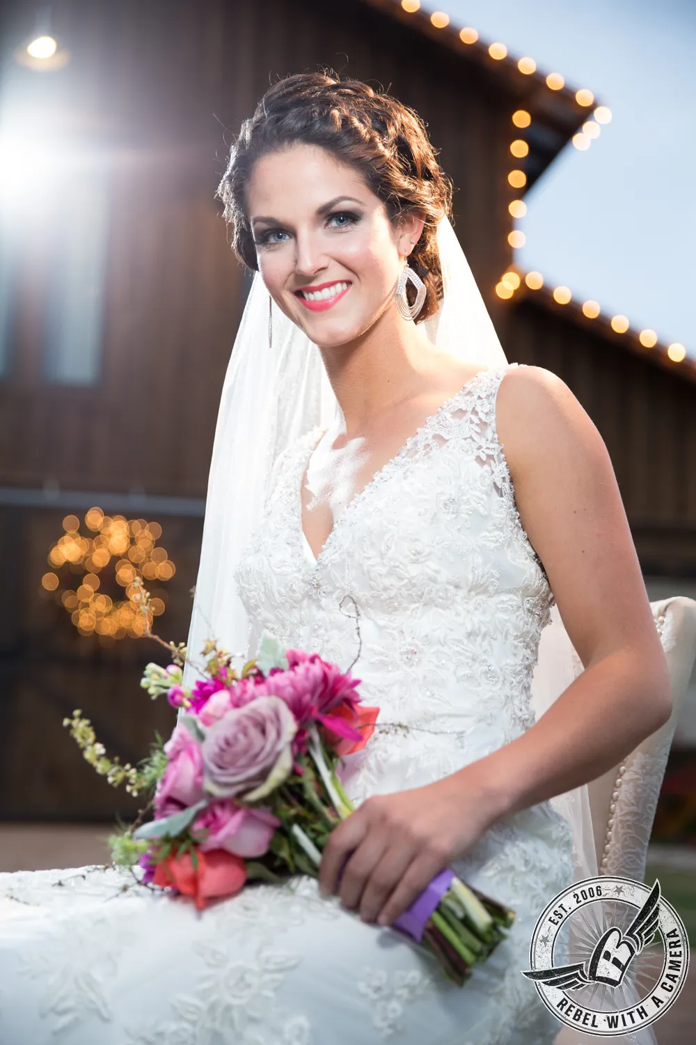 Bride holding a colorful bouquet in front of a lit wedding venue in Austin, TX.
