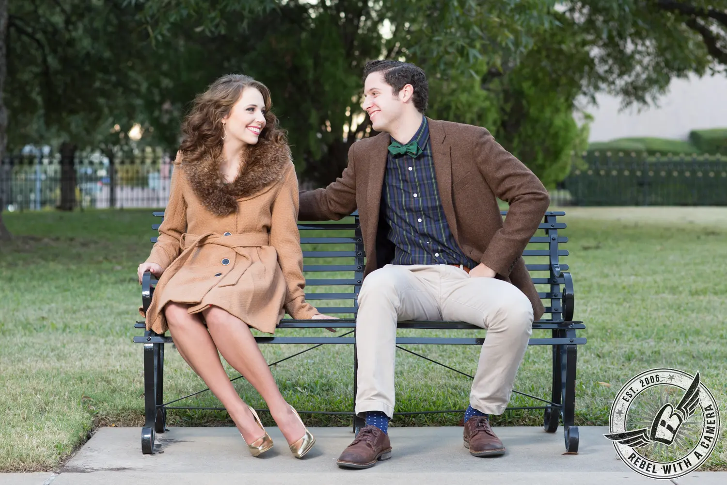Couple smiling at each other while sitting on a park bench in Austin, TX.