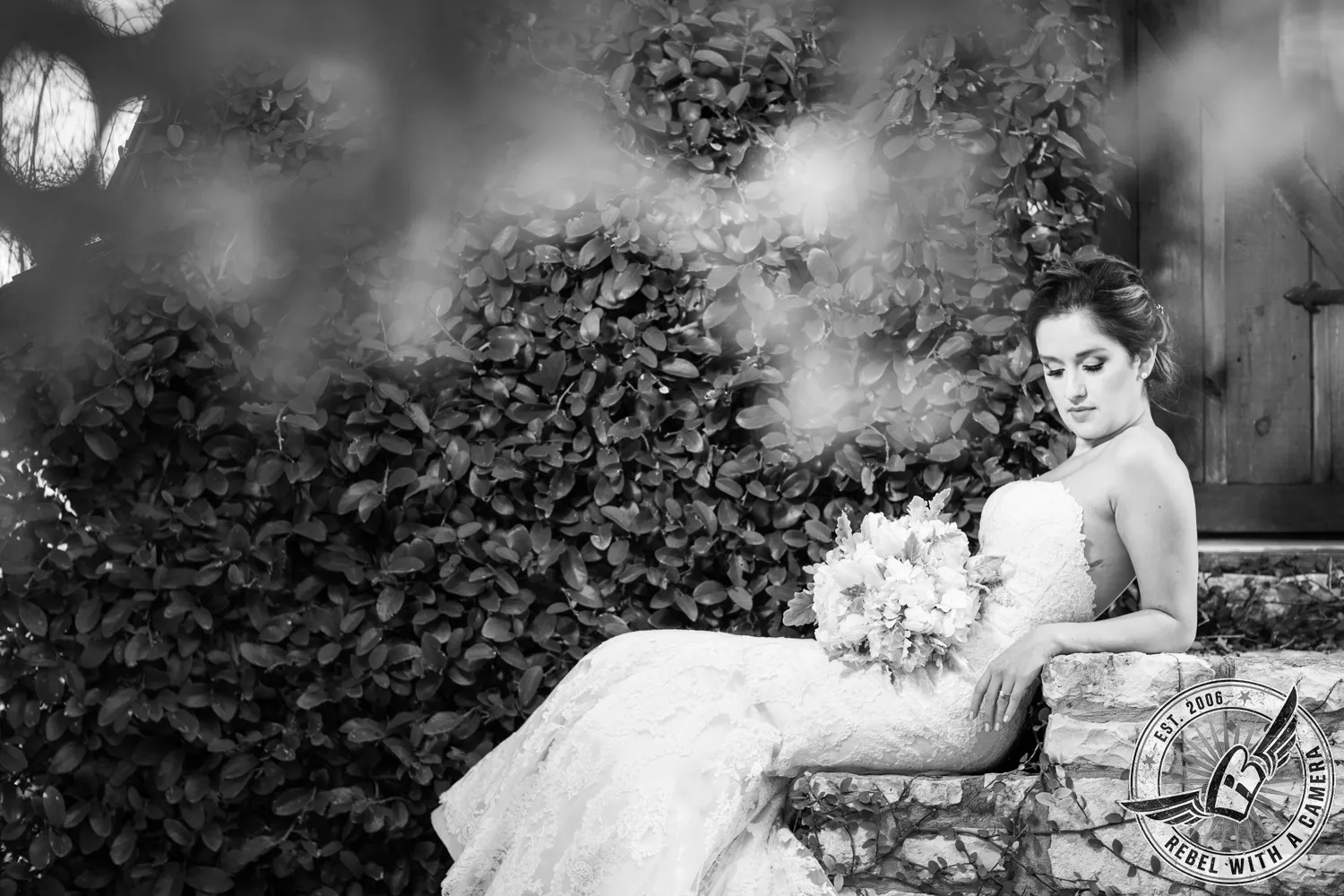 Black and white bride reclining on a stone wall with a bouquet in Austin, TX.