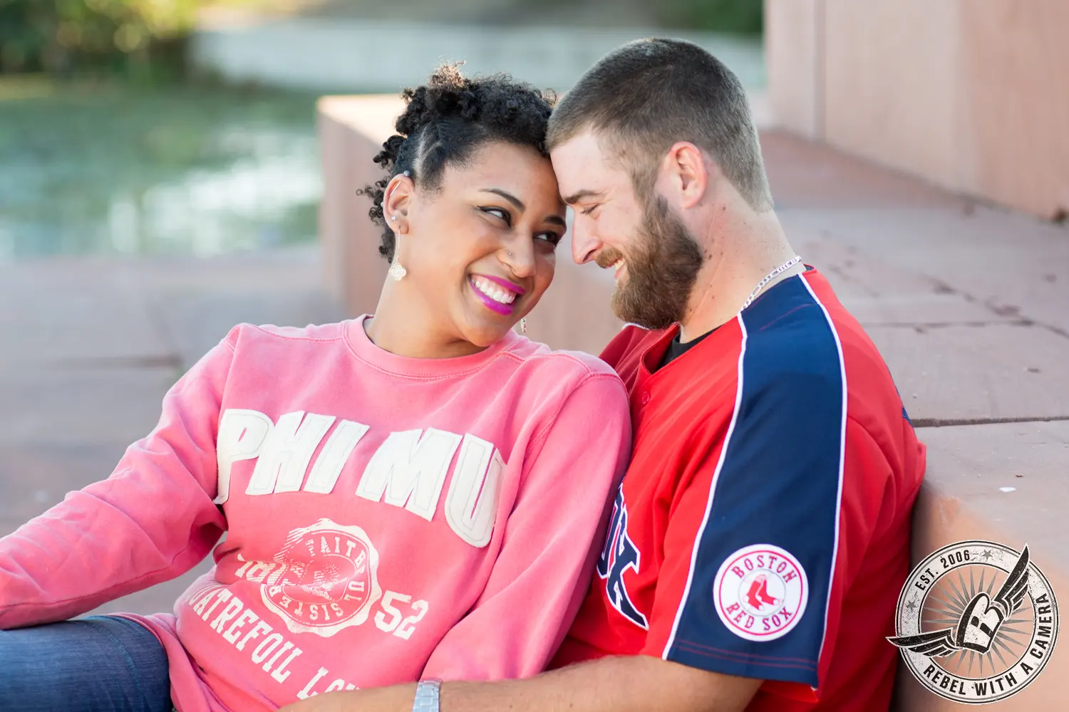 Smiling couple sitting together outdoors in Boston sports clothing in Austin, TX.