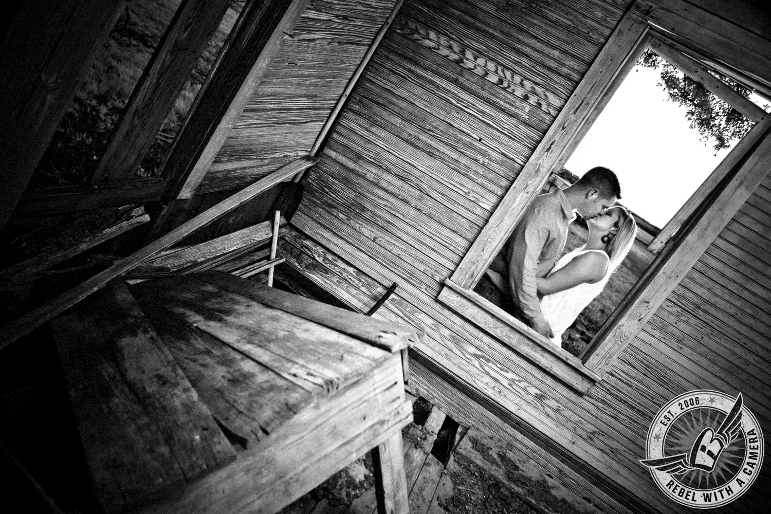 Black and white couple kissing through the window of a weathered wooden structure in Austin, TX.