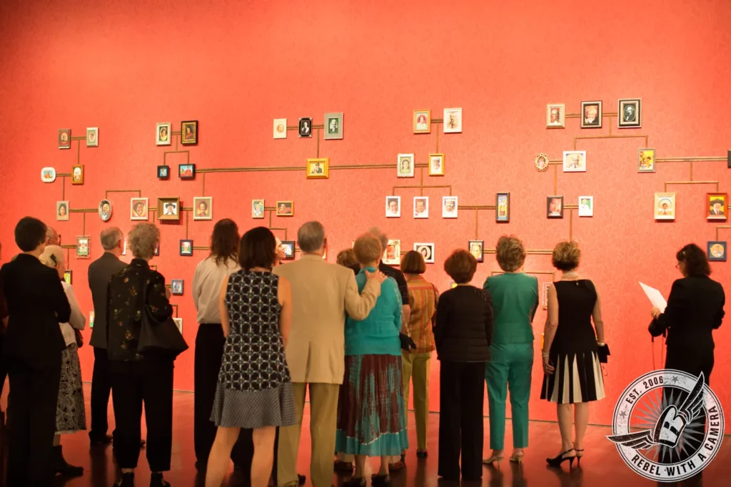 Museum visitors viewing a wall of framed portraits in Austin, TX.