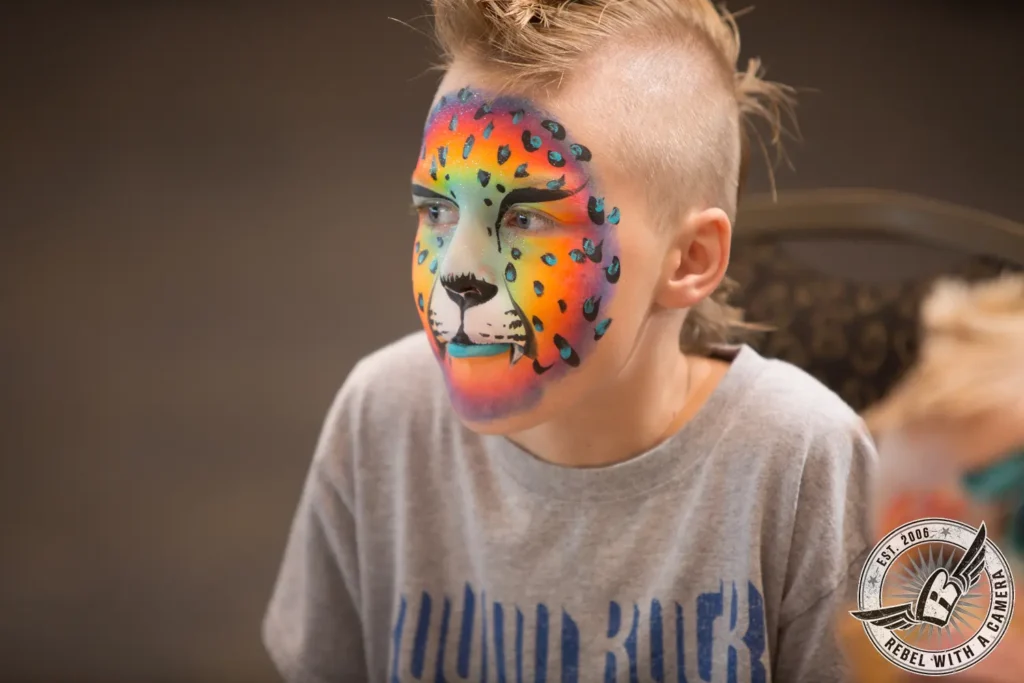 Child with colorful leopard face paint at Austin Summerfest