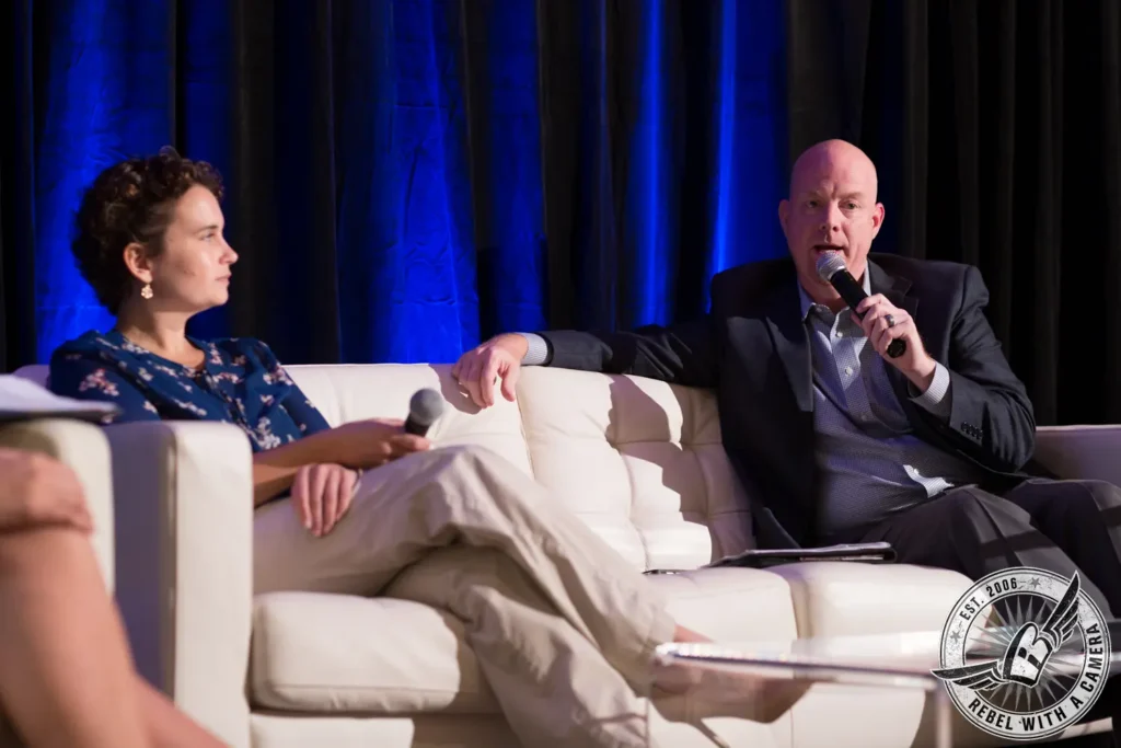 Two speakers holding microphones during a panel discussion in Austin, TX.