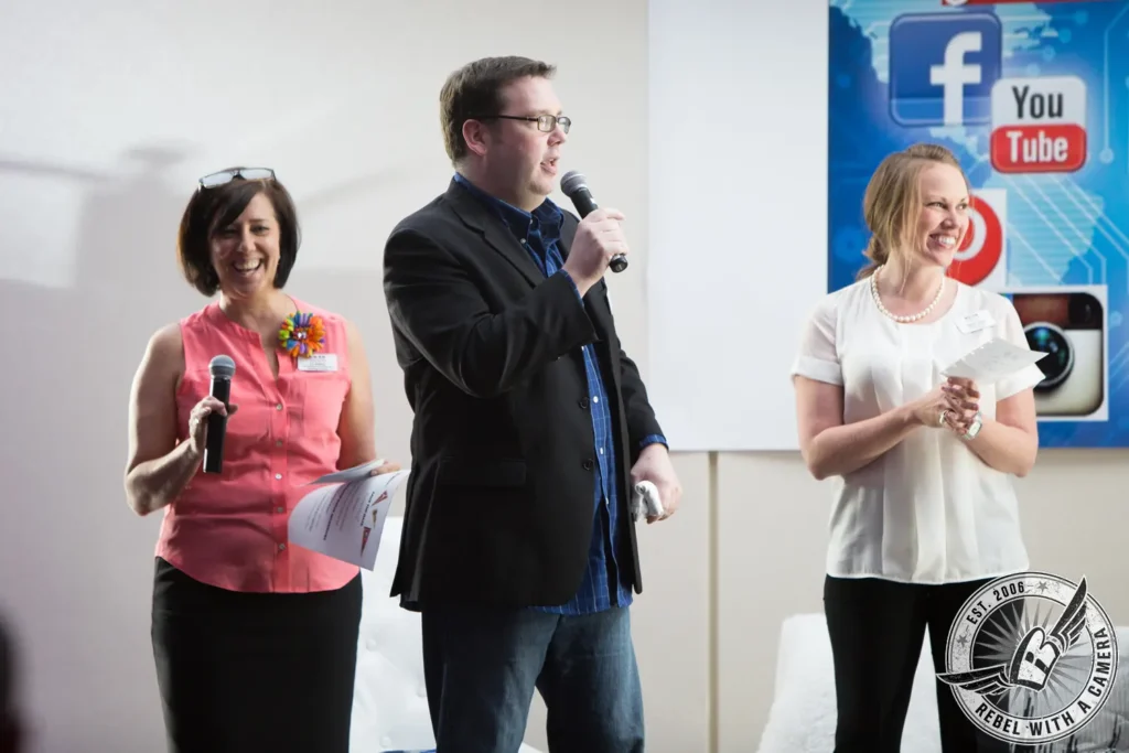 Three event presenters holding microphones and notes in Austin, TX.