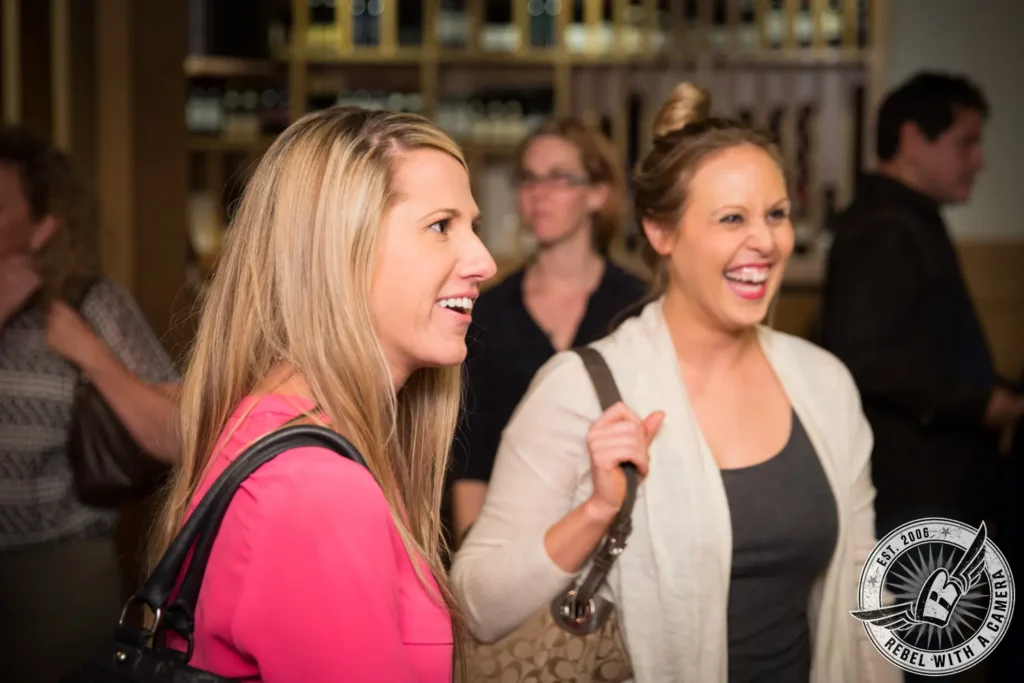 Two women smiling and talking at a corporate happy hour