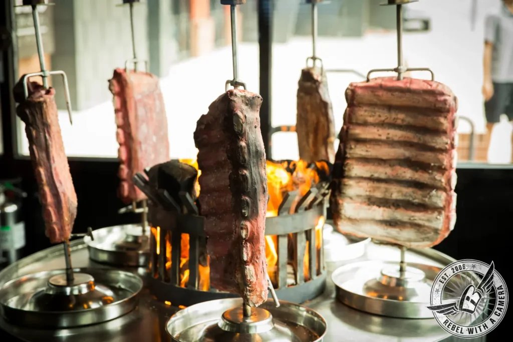 Rotisserie meat cooking over open flames at a corporate event in Austin, TX.