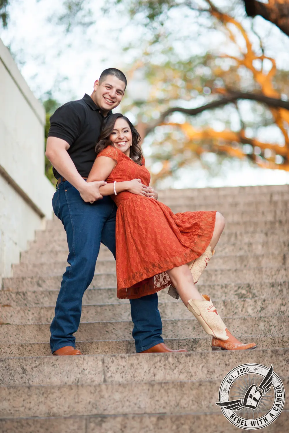 Couple posing on stone steps with a large oak tree behind them in Austin, TX.