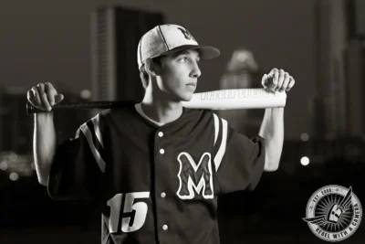 Jacob baseball senior portrait holding a bat in a dark uniform in Austin, TX.