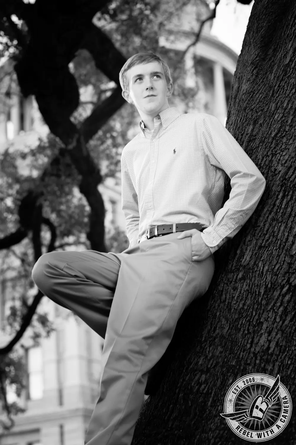 Black-and-white portrait of Johnathan leaning against a large tree near the Texas Capitol.