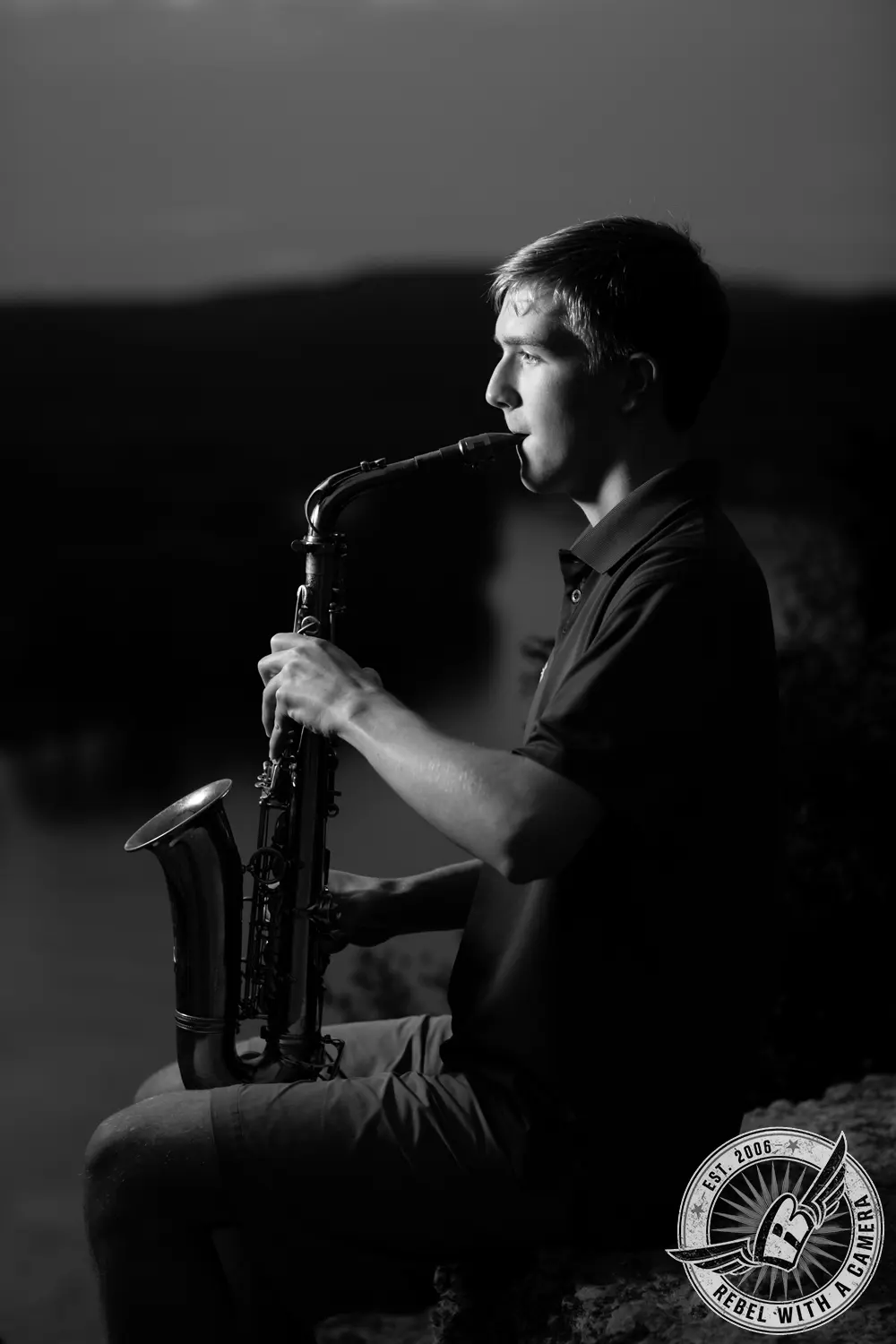 Black-and-white side portrait of Johnathan seated and playing a saxophone.