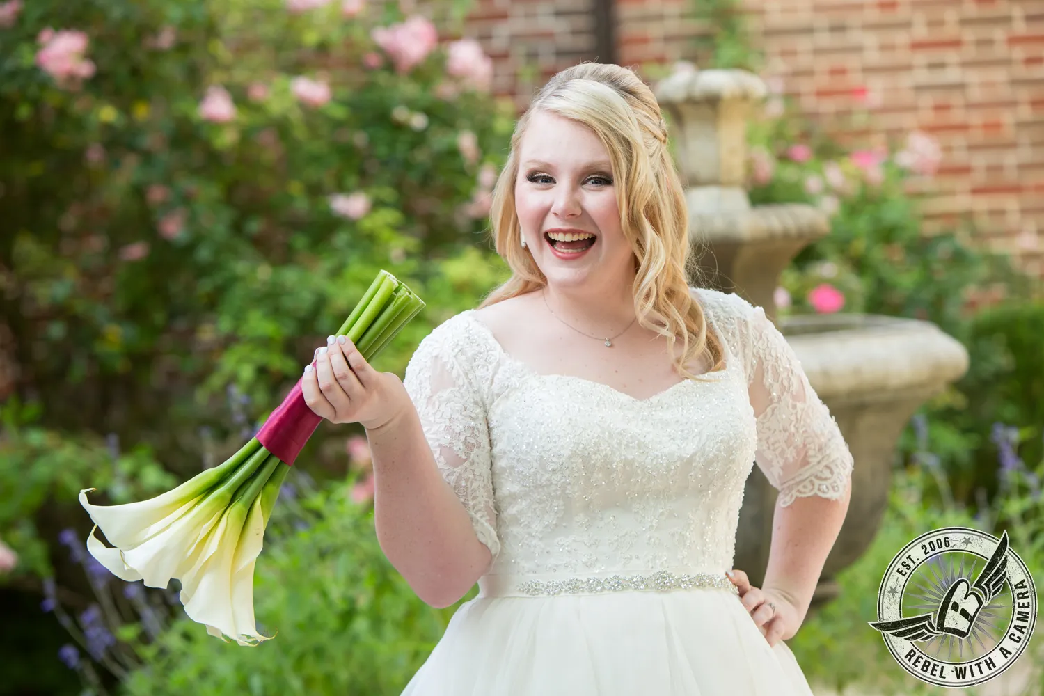 Smiling bride holding a bouquet of white calla lilies in a garden