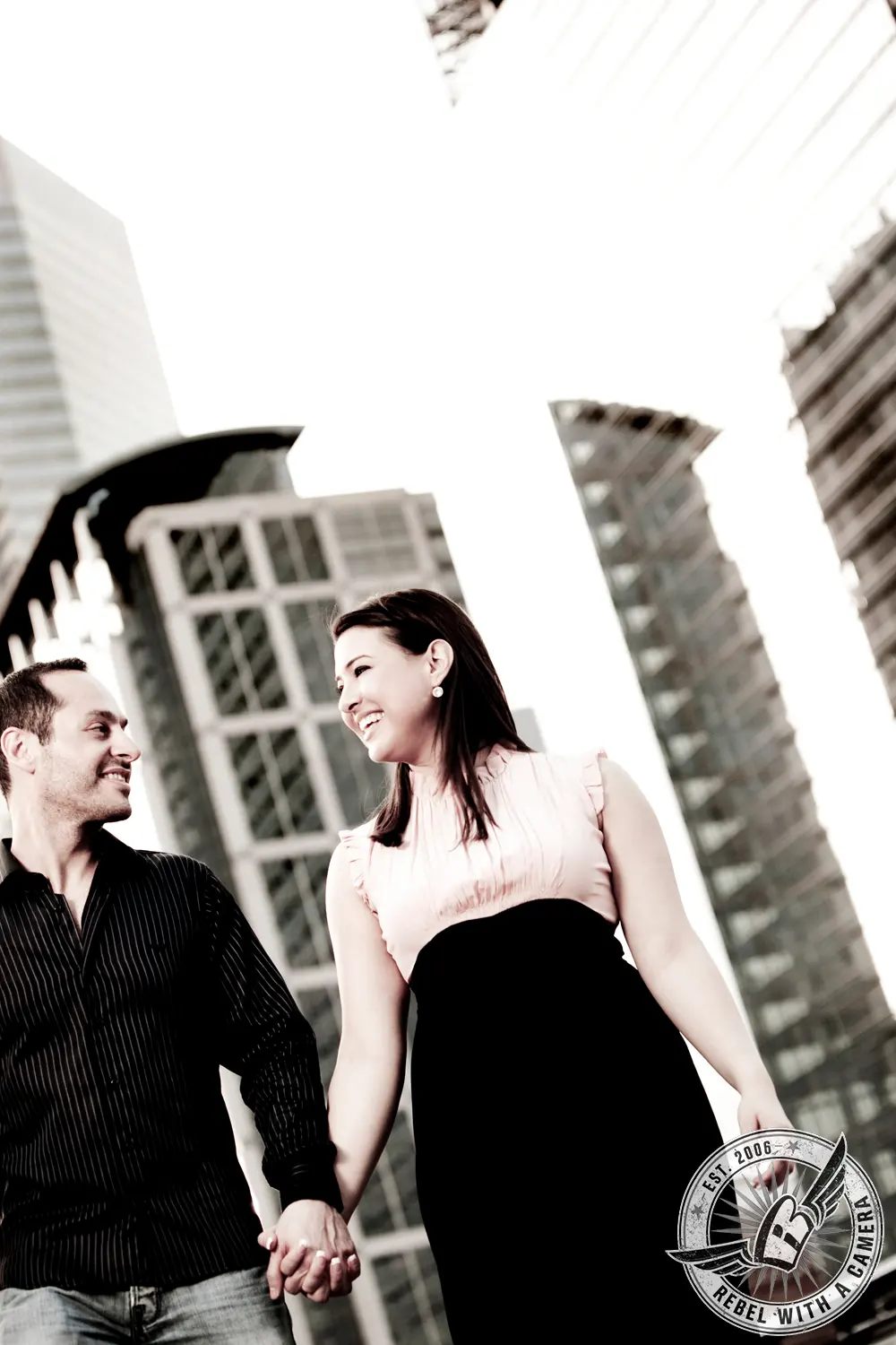 Couple holding hands and walking between downtown buildings in Austin, TX.