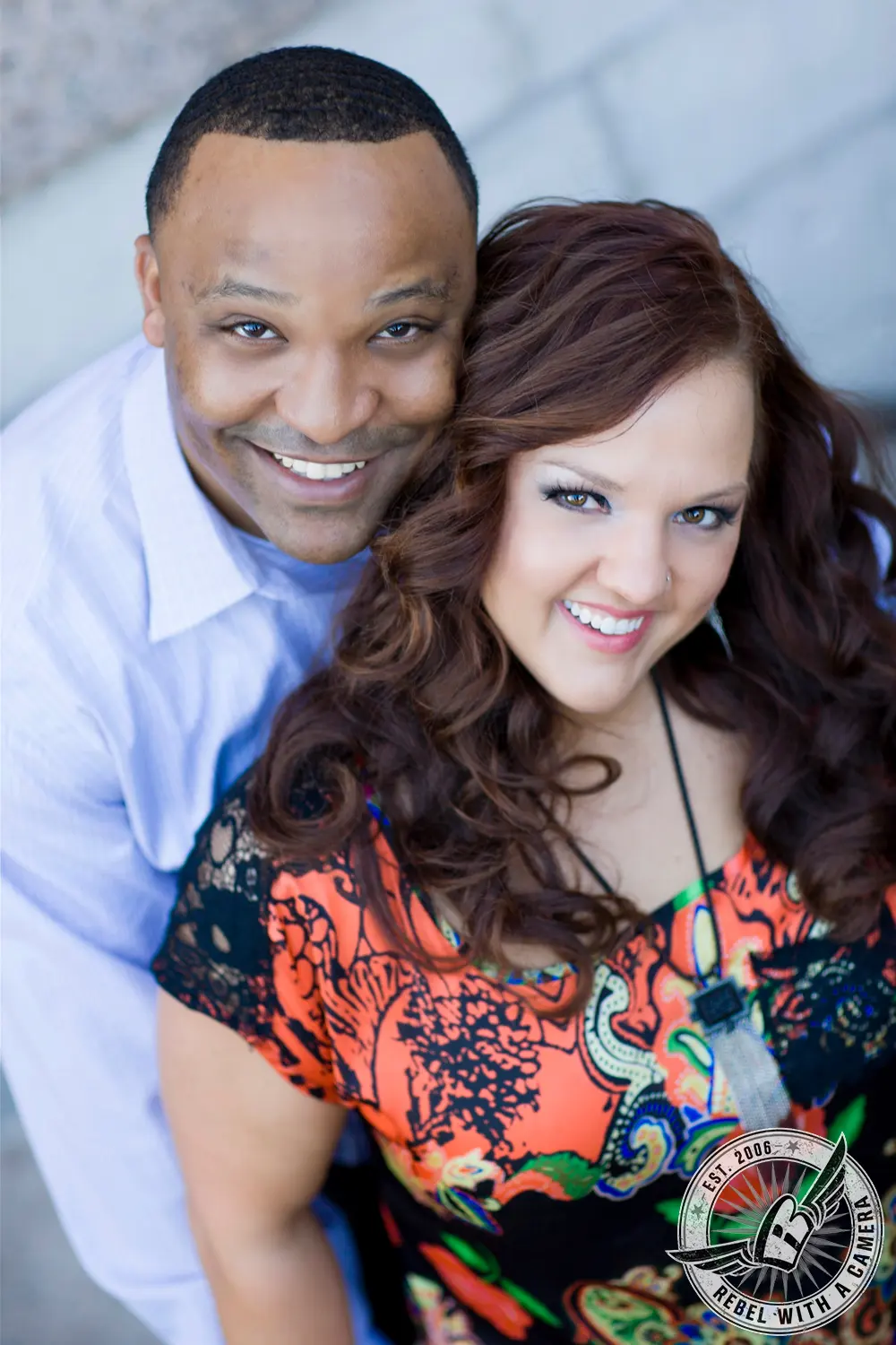 Smiling couple posing closely together in a colorful patterned outfit in Austin, TX.