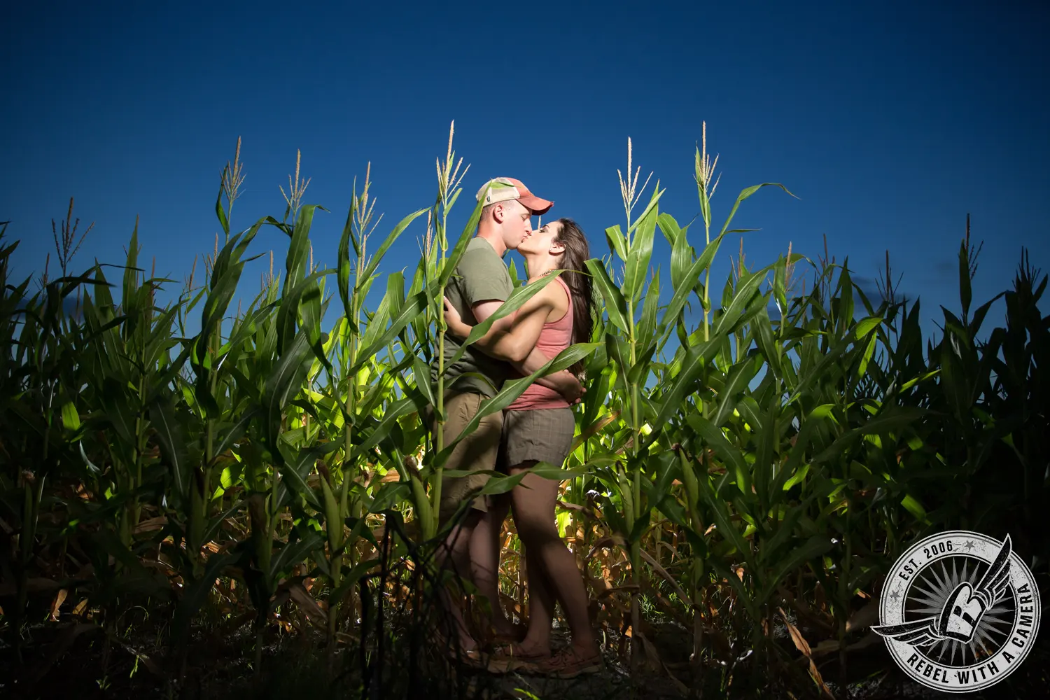 Couple kissing in a cornfield beneath a deep blue sky in Austin, TX.