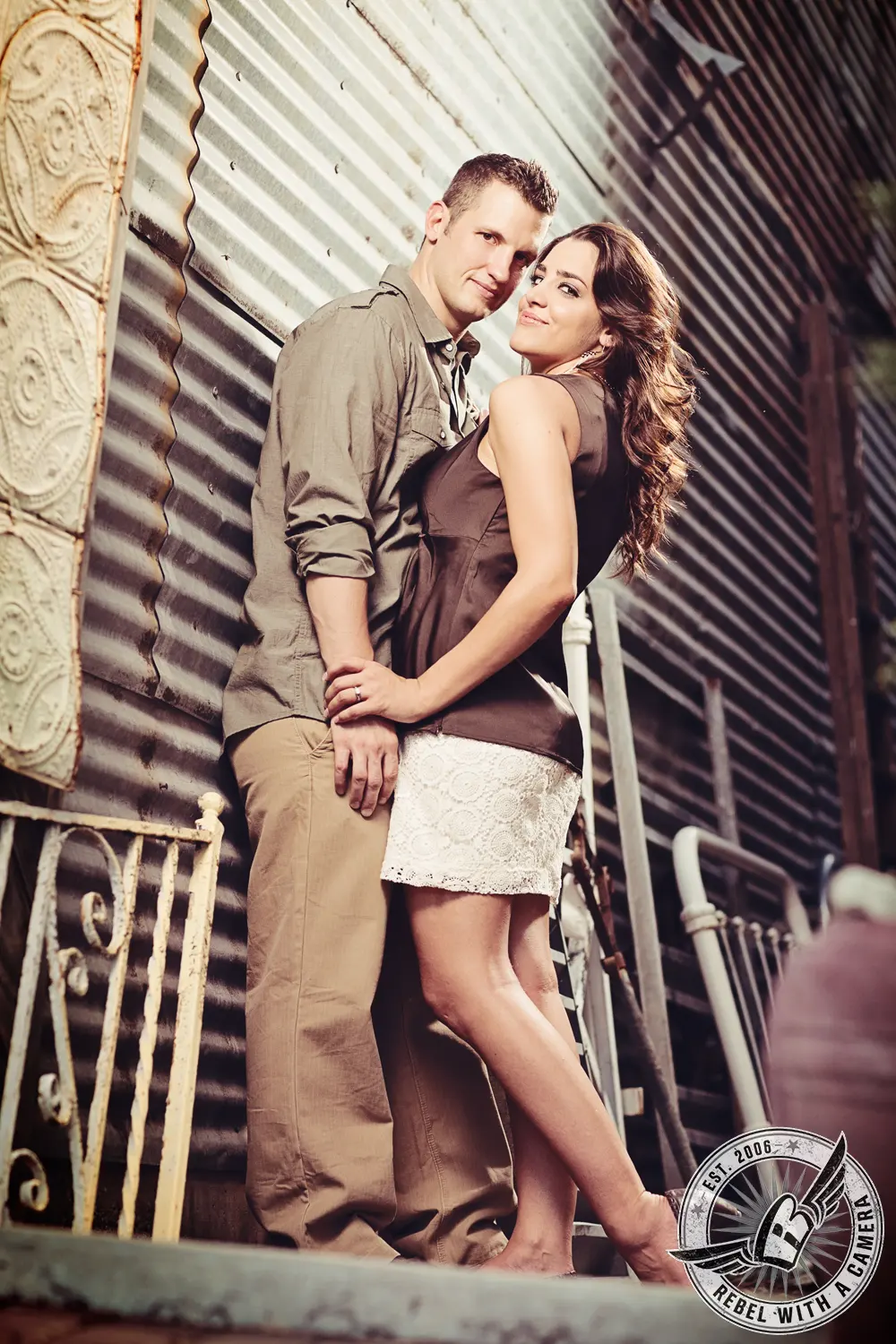 Couple embracing beside a corrugated metal wall in an urban setting in Austin, TX.
