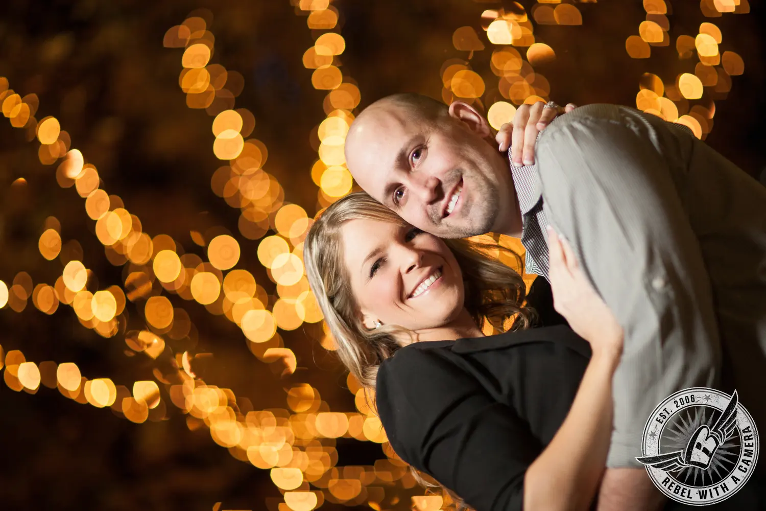 Couple embracing beneath warm string lights in Austin, TX.