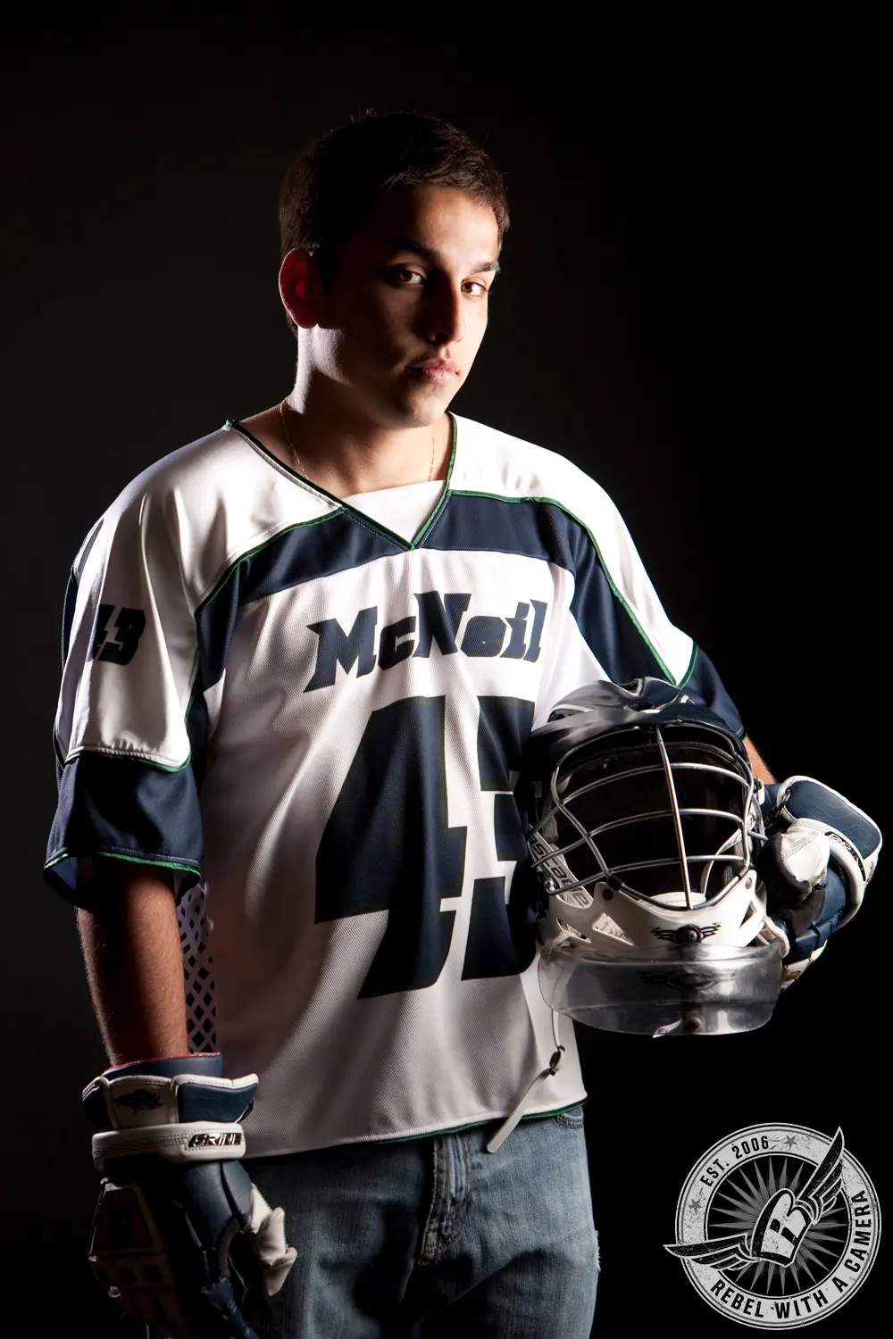 Studio portrait of Nick wearing a hockey jersey and gloves while holding a goalie mask.