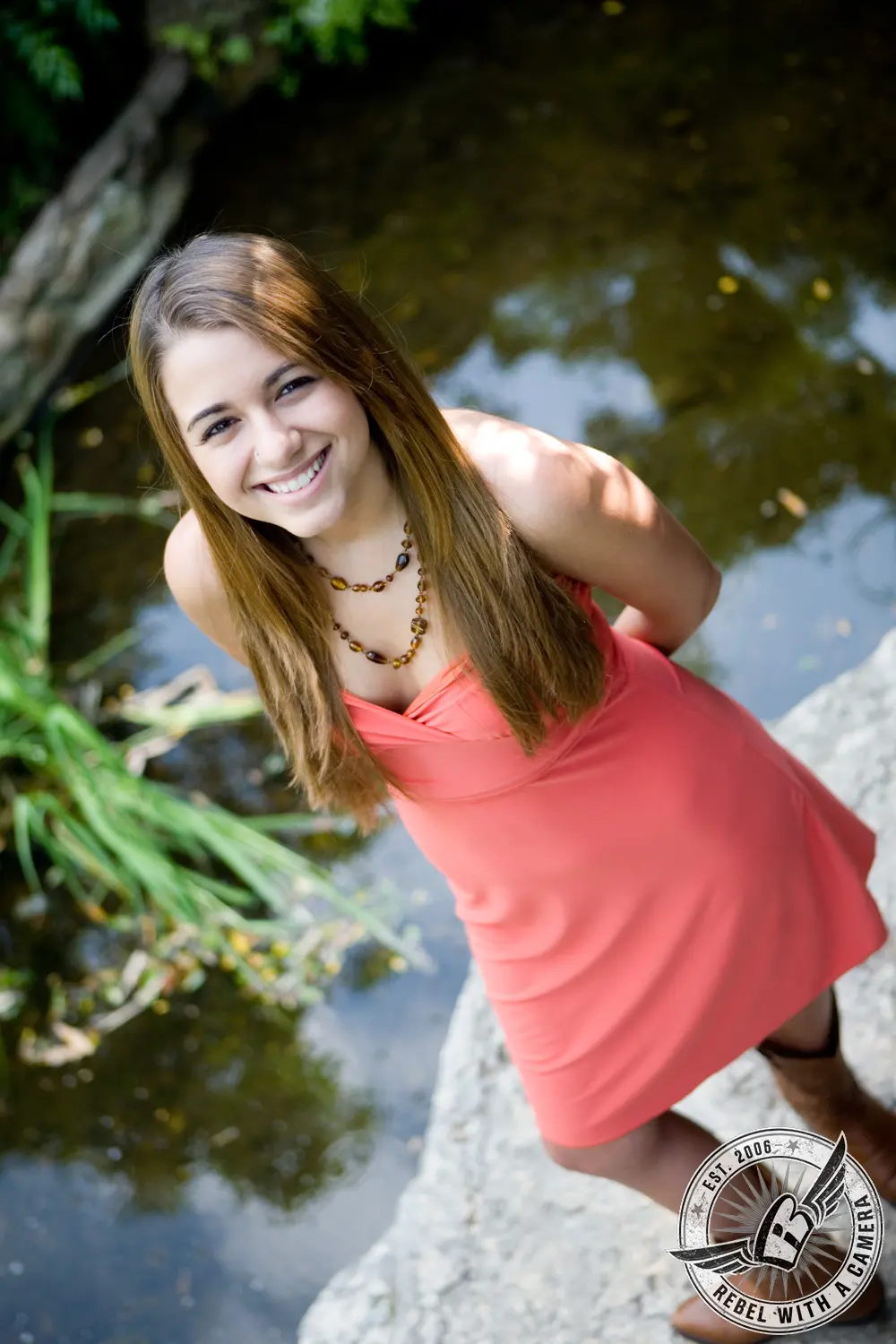 Ruby in a coral dress standing beside a pond at Zilker Botanical Gardens.