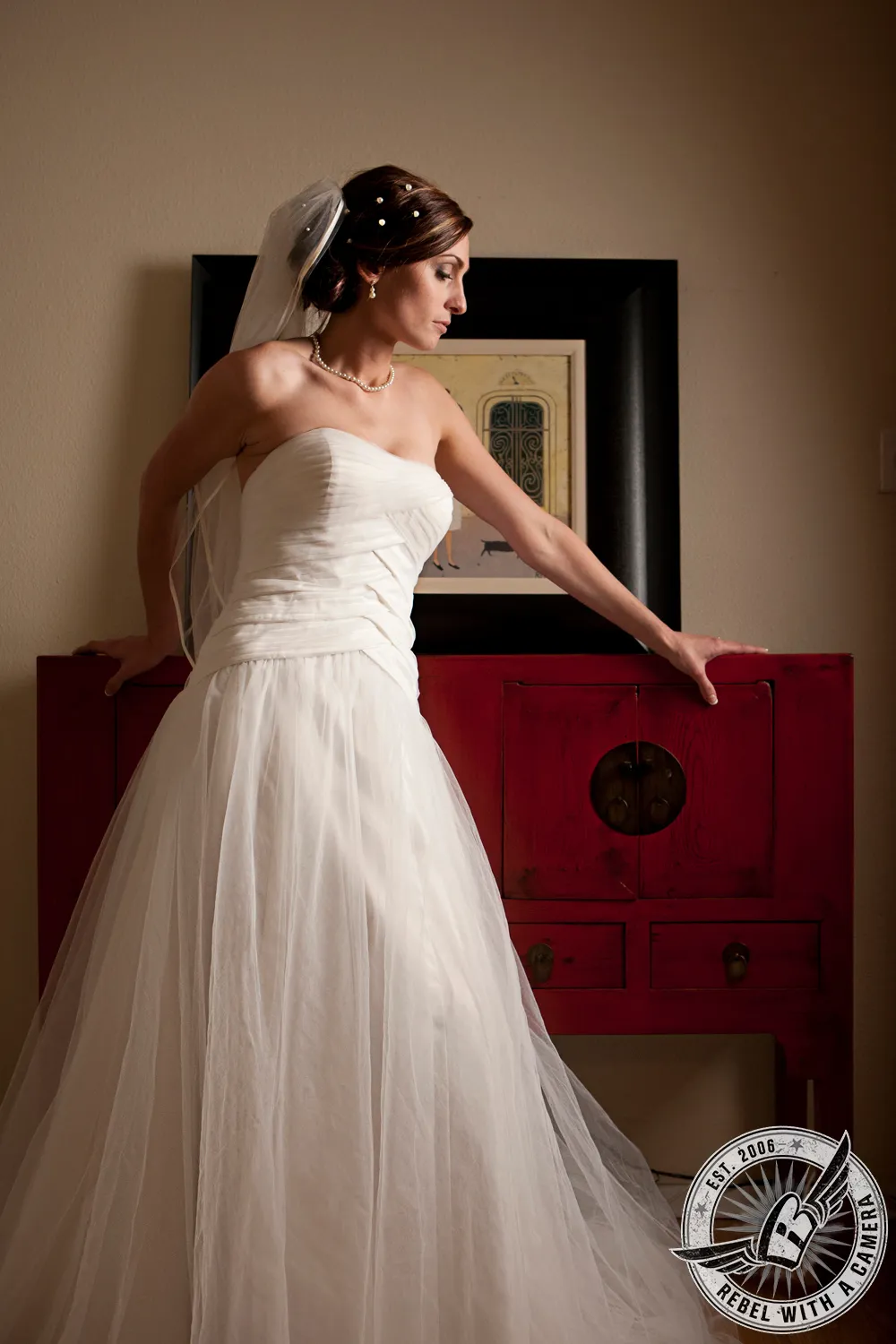 Bride in a white wedding dress posing beside a red cabinet in Austin, Texas.